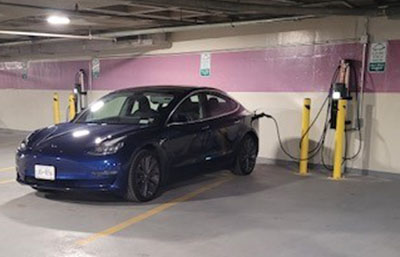 A blue electric car plugged into a charging station in the Innovation Square parking garage.