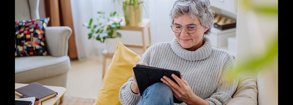 Woman lounging on couch reading on a tablet.