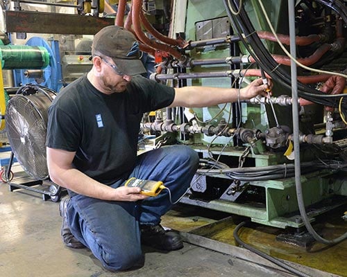 A man using a handheld device to test equipment.