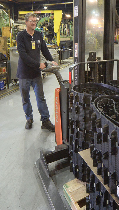 A man moving tire parts on a pallet-jack.