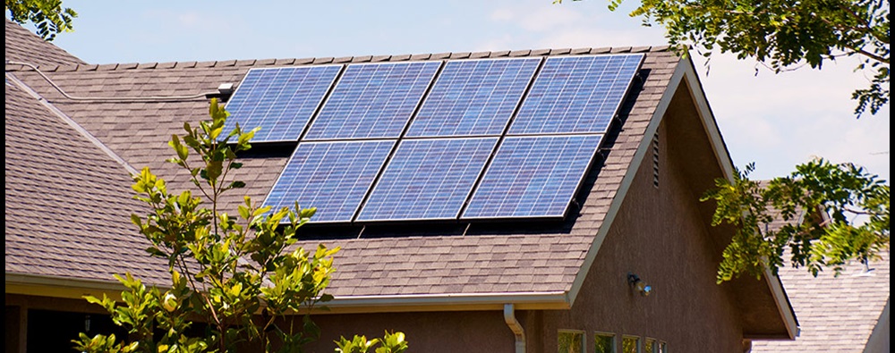 Solar panels mounted on the roof of a house with brown shingles.